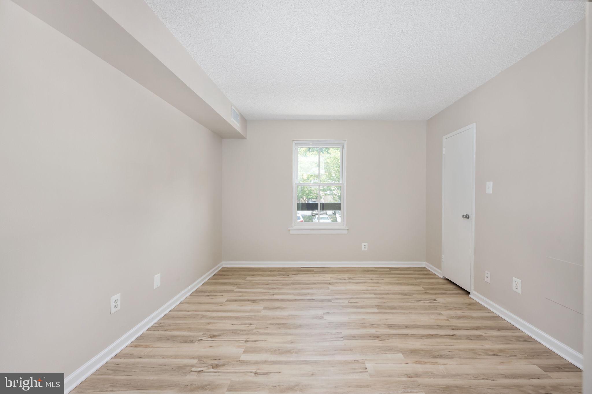 11659 Stoneview Square, Unit 11C Reston, VA 20191 - Photo 26 of 50 a view of an empty room with wooden floor and a window