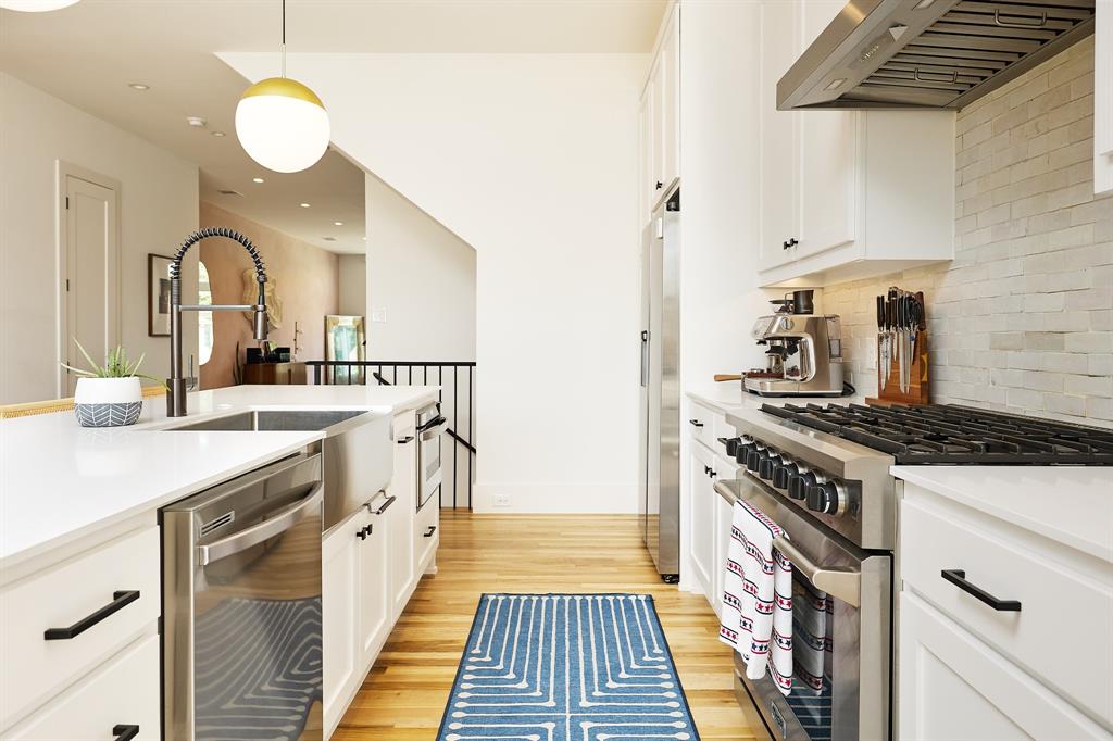 1844 Mecca Street Dallas, TX 75206 - Photo 11 of 33 Brand new appliances with stainless steel finishes, exhaust hood, white cabinets, light wood-style floors, and pendant lighting