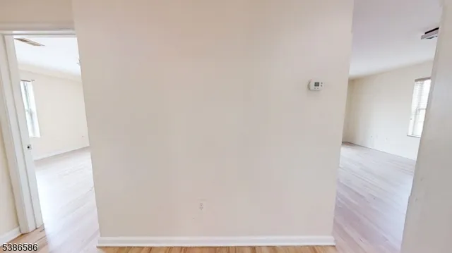 a view of a hallway with wooden floor and a bathroom