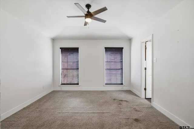 an empty room with windows and fan
