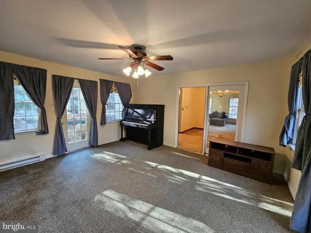 an empty room with windows fireplace and a chandelier fan