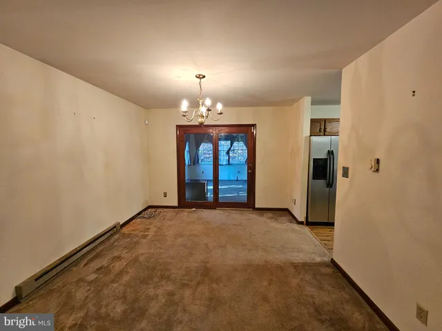 a view of an empty room with window and chandelier