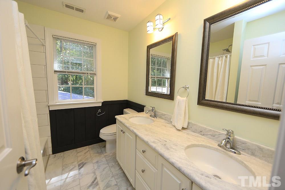 5921 Wild Orchid Trail Raleigh, NC 27613 - Photo 22 of 30 Hall bath with framed mirrors, updated vanity and tiled floor.