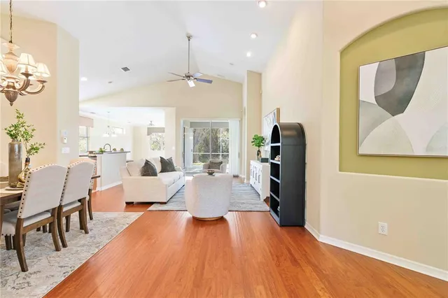 a dining room with wooden floor a chandelier a glass table and chairs