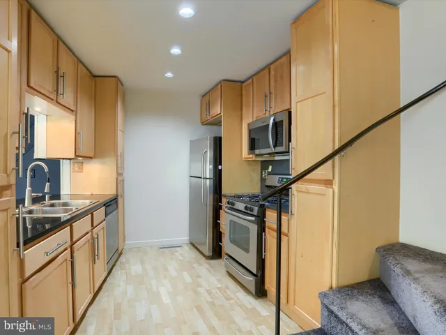 a kitchen with stainless steel appliances granite countertop a sink a stove a refrigerator cabinets and a kitchen island