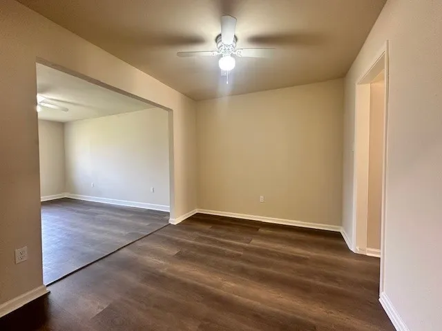 an empty room with wooden floor and a ceiling fan