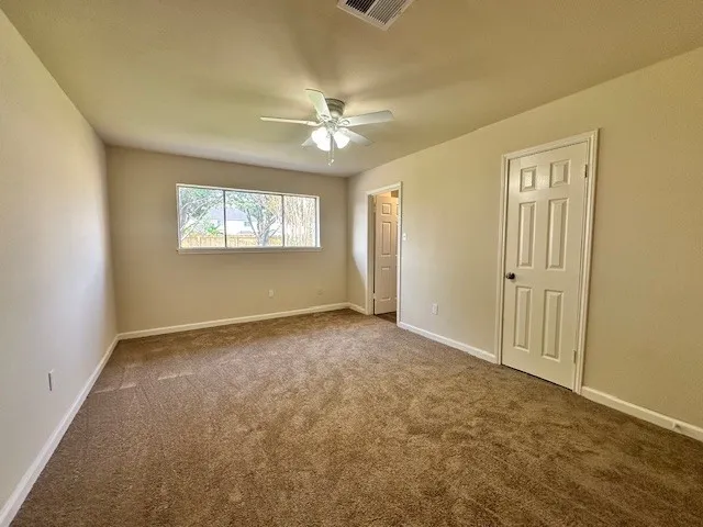 an empty room with windows and fan