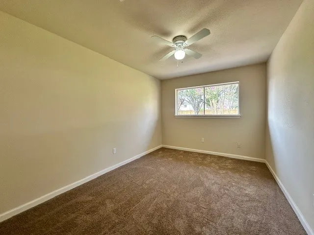 an empty room with windows and fan
