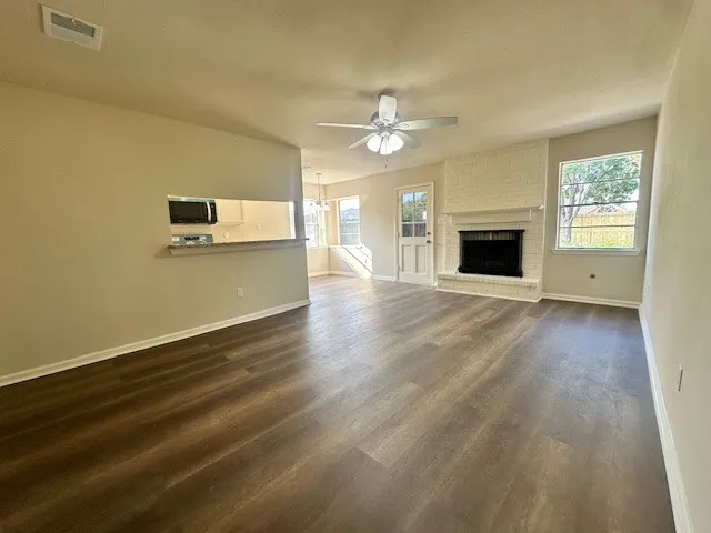 an empty room with wooden floor fireplace and windows