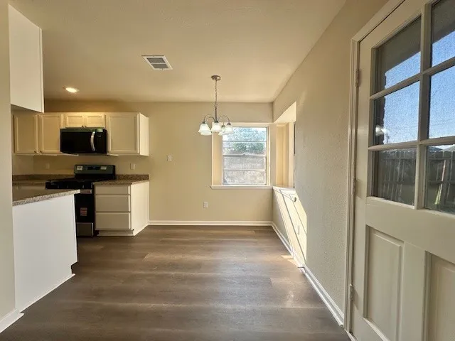 a kitchen with granite countertop a refrigerator and a stove top oven
