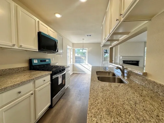 a kitchen with granite countertop a sink and a stove top oven