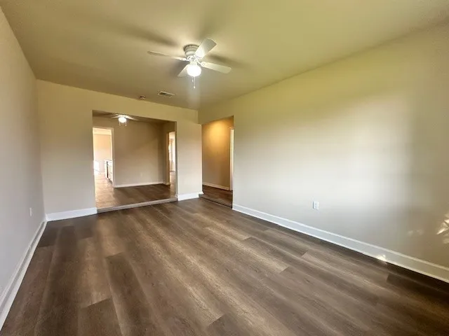 an empty room with wooden floor and fan