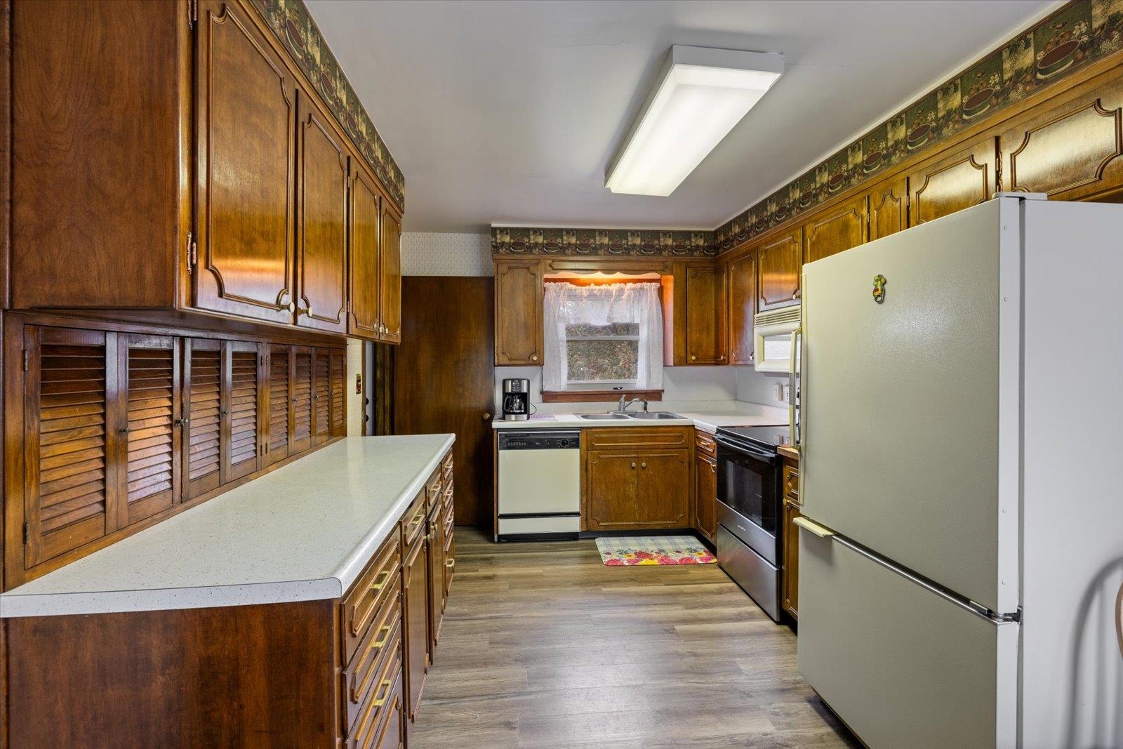 813 6th Street South Virginia, MN 55792 - Photo 14 of 44 Kitchen featuring white appliances, light countertops, dark wood-style flooring, and brown cabinetry