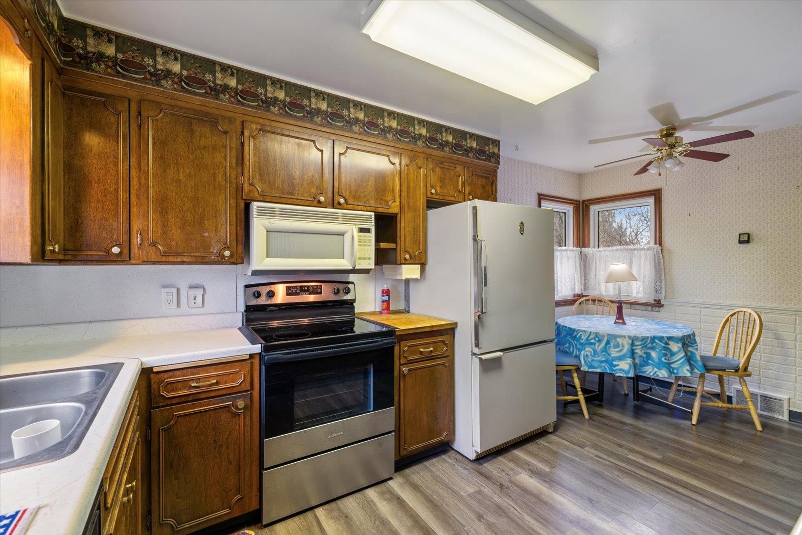 813 6th Street South Virginia, MN 55792 - Photo 17 of 44 Kitchen featuring wallpapered walls, white appliances, light wood-style floors, light countertops, and a wainscoted wall