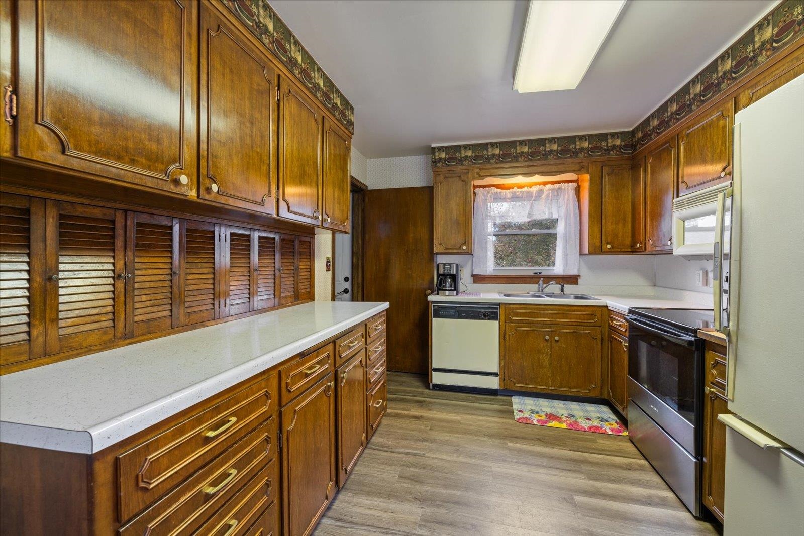 813 6th Street South Virginia, MN 55792 - Photo 18 of 44 Kitchen with light countertops, white appliances, light wood-type flooring, and brown cabinetry