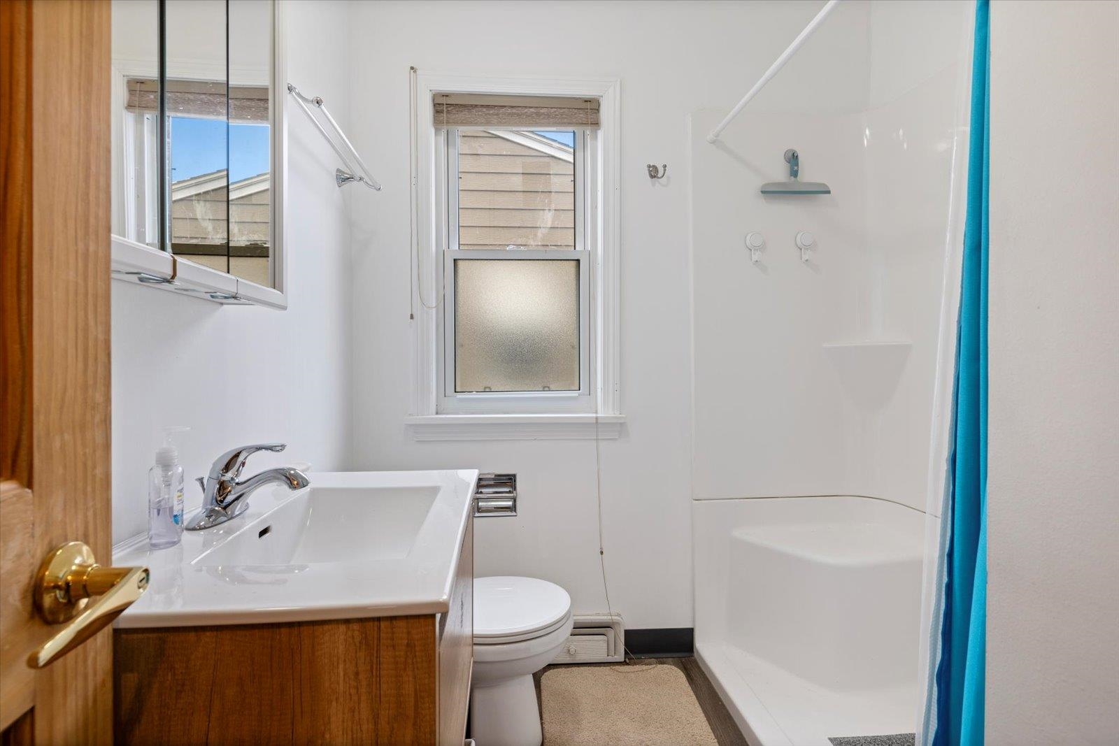 813 6th Street South Virginia, MN 55792 - Photo 32 of 44 Full bathroom featuring curtained shower, vanity, and a baseboard radiator