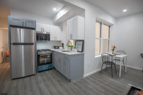 a kitchen with a refrigerator wooden floor a dining table and chairs