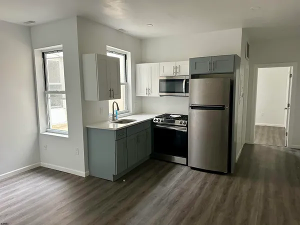 a kitchen with a refrigerator a stove top oven and wooden floor