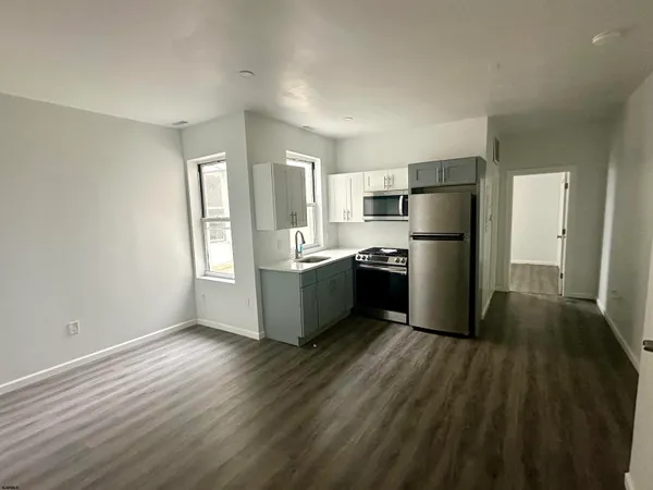 a kitchen with a refrigerator a sink and dishwasher with wooden floor