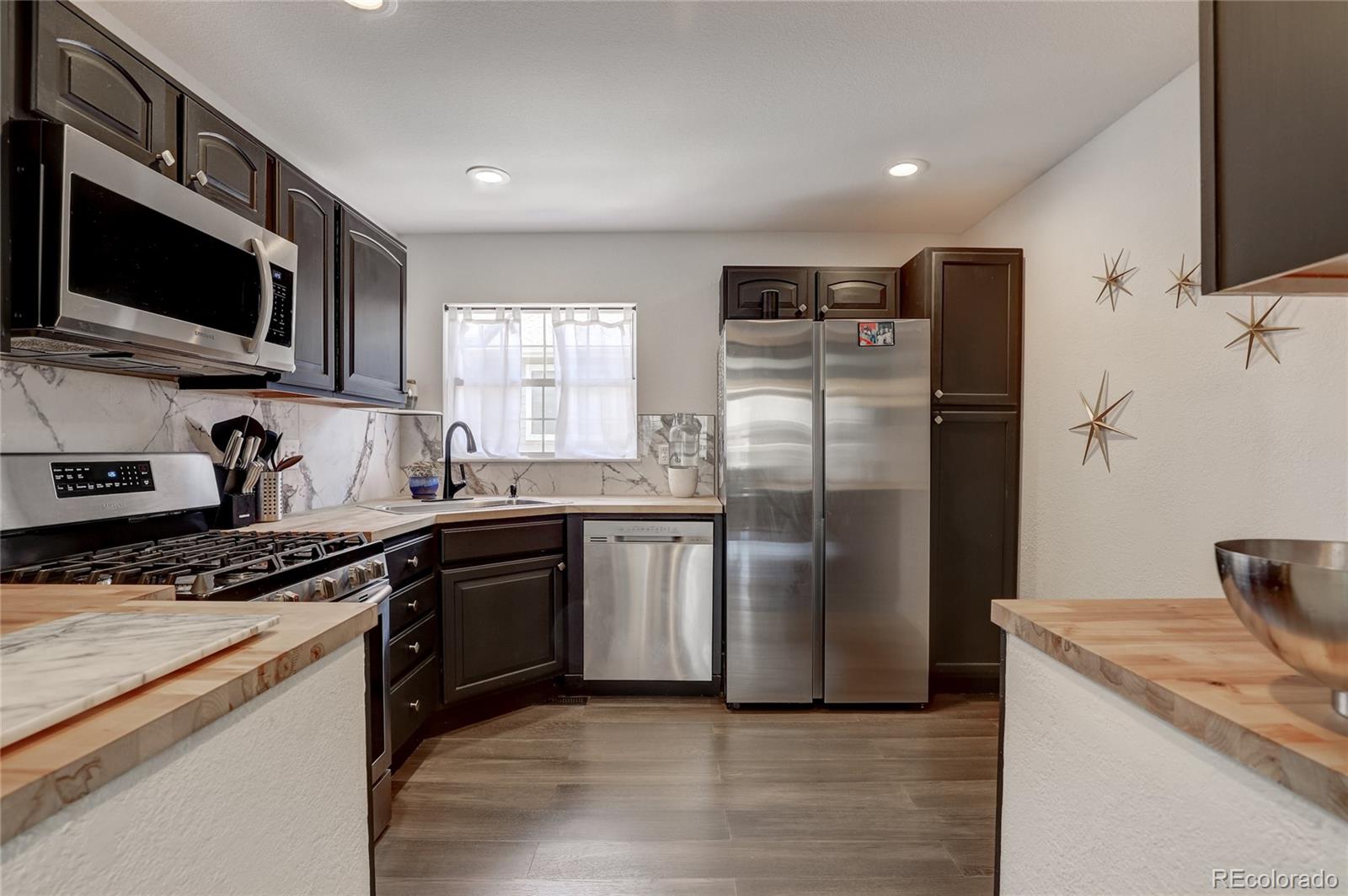 6120 Trailhead Road Highlands Ranch, CO 80130 - Photo 2 of 29 a kitchen with stainless steel appliances granite countertop a stove top oven a refrigerator and a sink