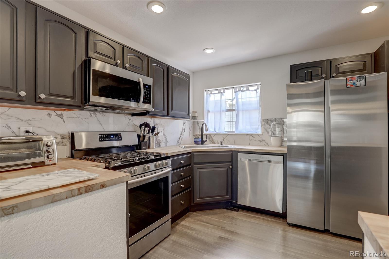 6120 Trailhead Road Highlands Ranch, CO 80130 - Photo 10 of 29 a kitchen with stainless steel appliances granite countertop a stove a sink dishwasher a refrigerator and a microwave oven