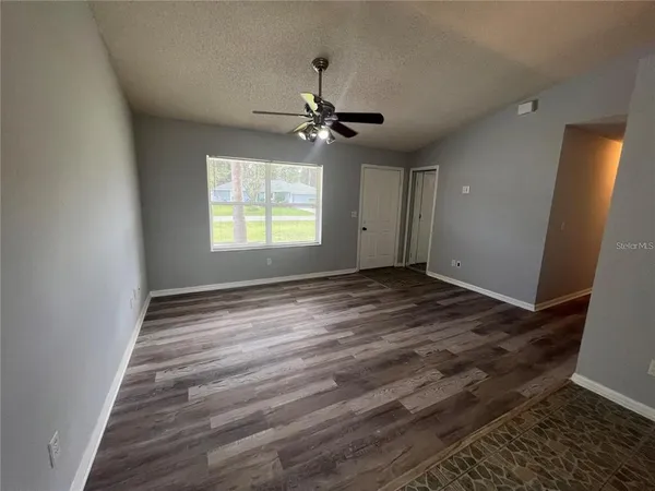 an empty room with windows and fan