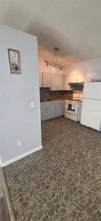 a view of a refrigerator in kitchen and an empty room