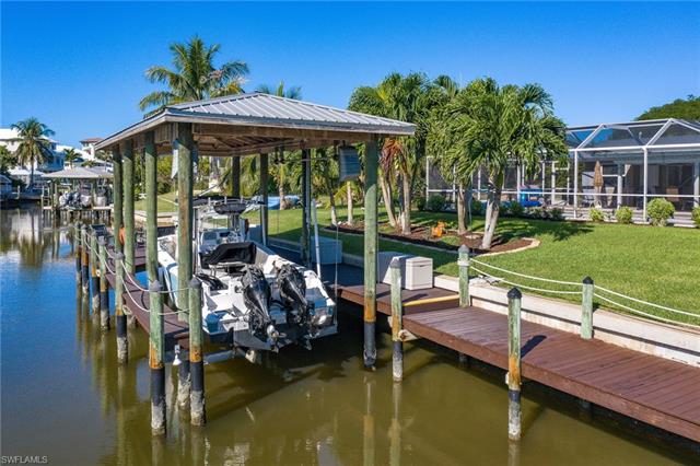 8522 Lagoon Road Fort Myers Beach, FL 33931 - Photo 7 of 32 Extra large dock with boat lift and metal roof canopy, sitting area with fish cleaning station.