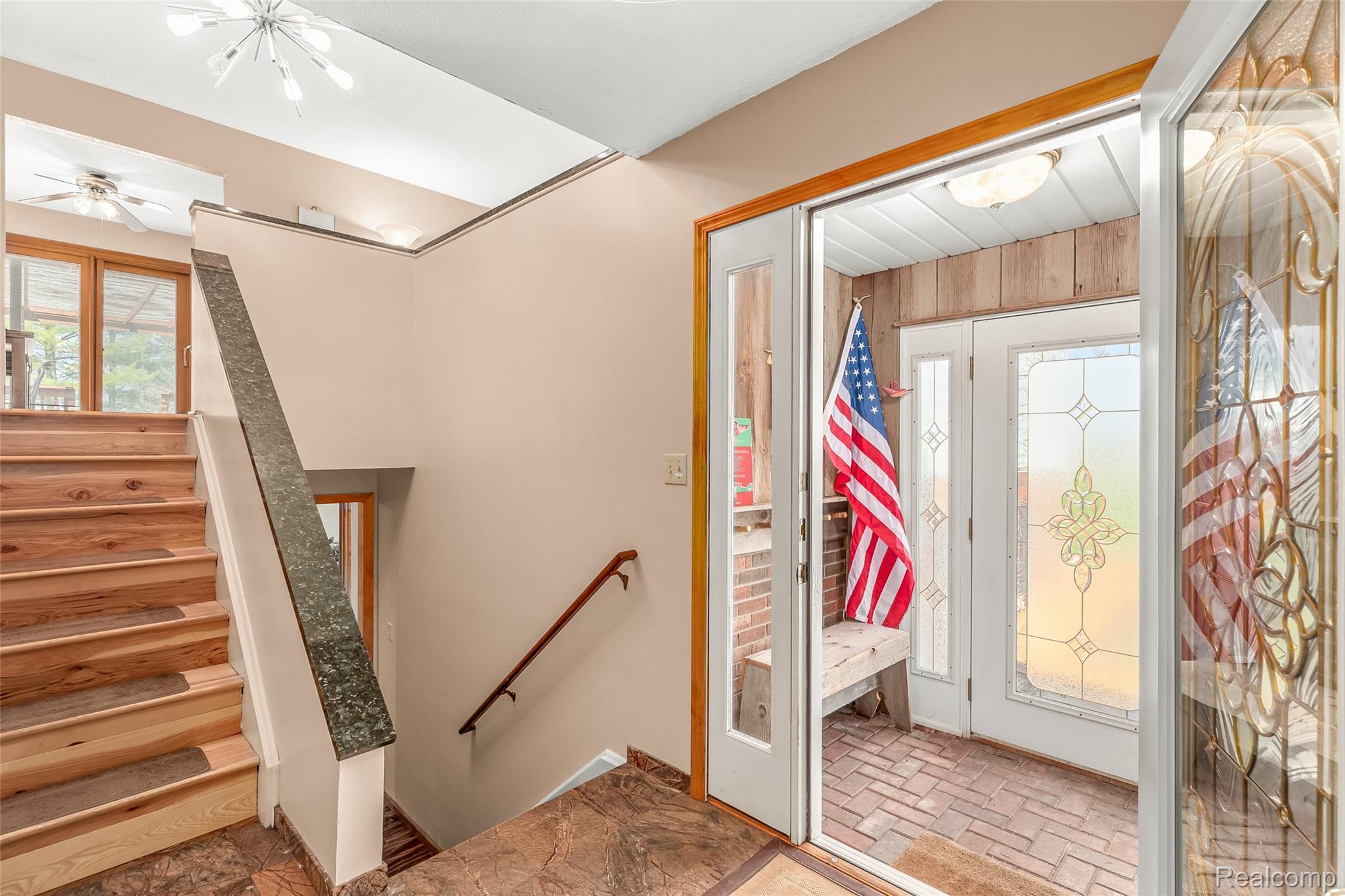 15395 Osius Road Chelsea, MI 48118 - Photo 2 of 55 Entryway featuring a decorative glass door, tiled flooring, wood-finish stairs with a dark banister, and a contemporary ceiling light fixture