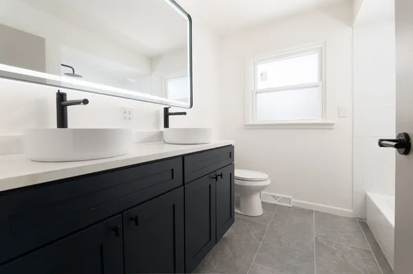 a bathroom with a granite countertop sink a toilet and a mirror