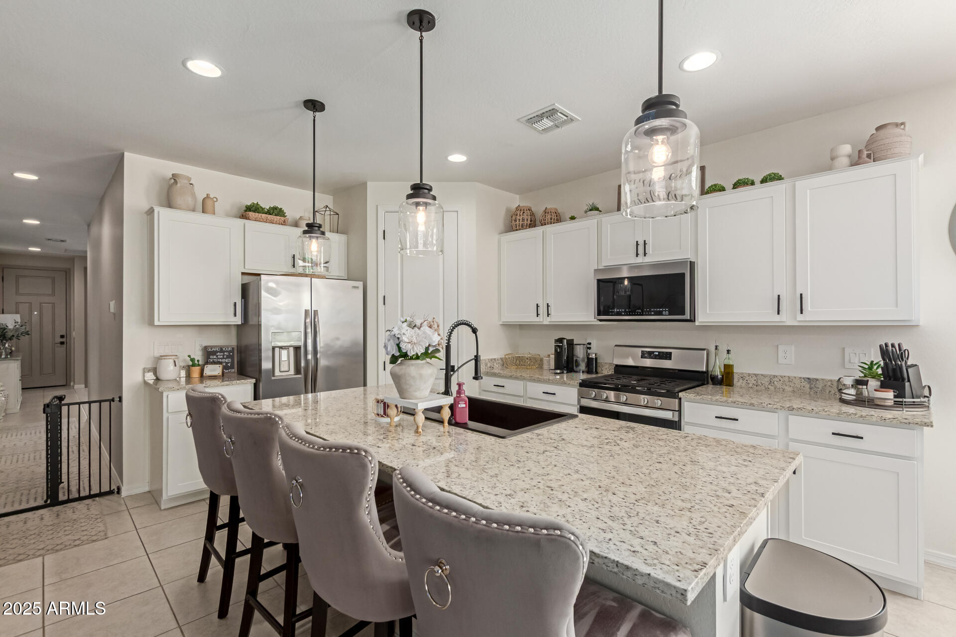 11534 East Unity Avenue Mesa, AZ 85212 - Photo 3 of 22 a kitchen with stainless steel appliances kitchen island granite countertop a table chairs stove and white cabinets