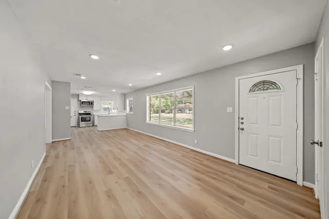 a view of empty room with kitchen and window