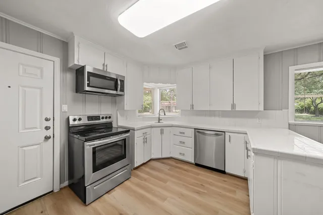 a kitchen with cabinets stainless steel appliances a sink and a wooden floor