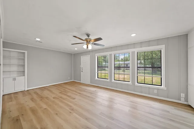 a view of an empty room with a window and wooden floor