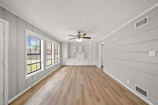 a view of an empty room with a window and wooden floor