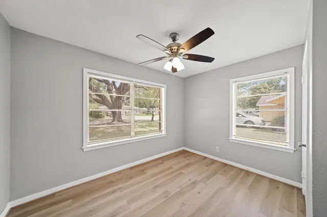 a view of an empty room with a window and wooden floor