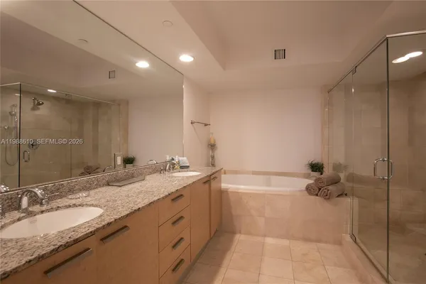 a bathroom with a granite countertop sink a mirror and a bathtub