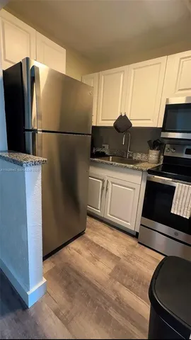 a kitchen with stainless steel appliances granite countertop a refrigerator sink and white cabinets