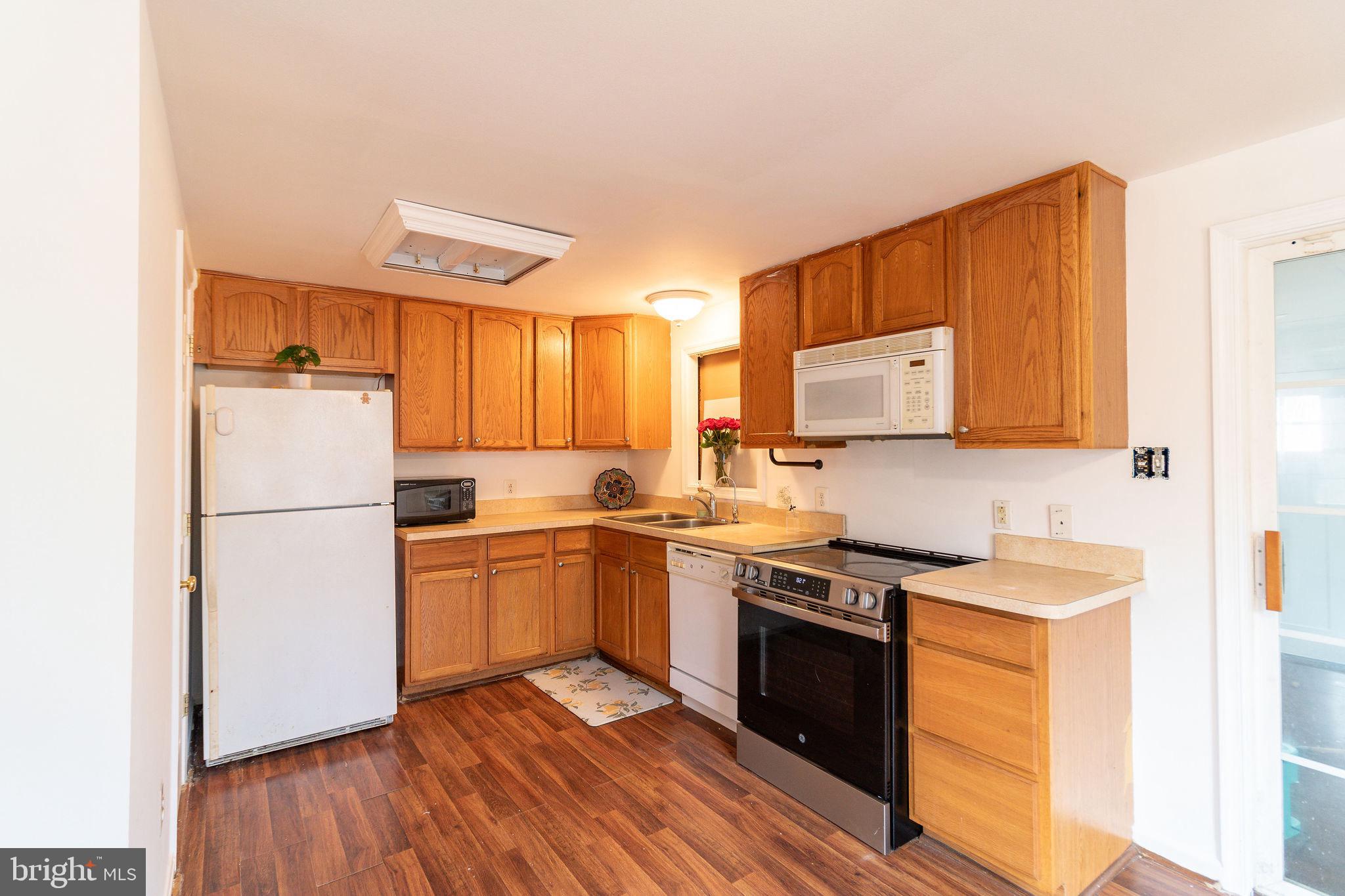 16 Eley Road Fredericksburg, VA 22406 - Photo 8 of 16 a kitchen with a sink a refrigerator a microwave oven and a stove with wooden floor