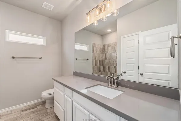 a bathroom with a granite countertop sink a toilet and a large mirror