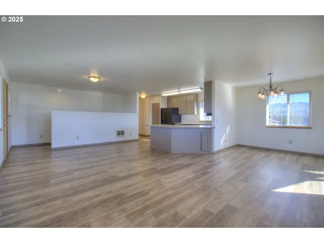 a view of kitchen and empty room with wooden floor