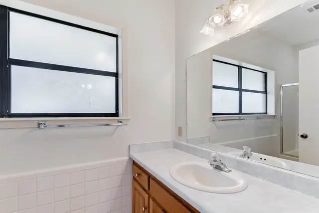 a bathroom with a sink and mirror with bathtub