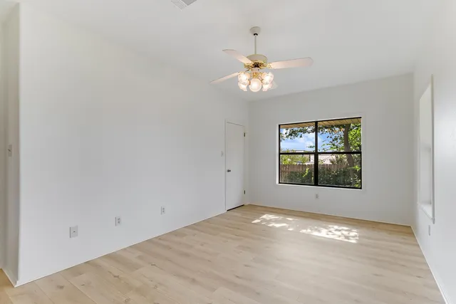 an empty room with windows and fan