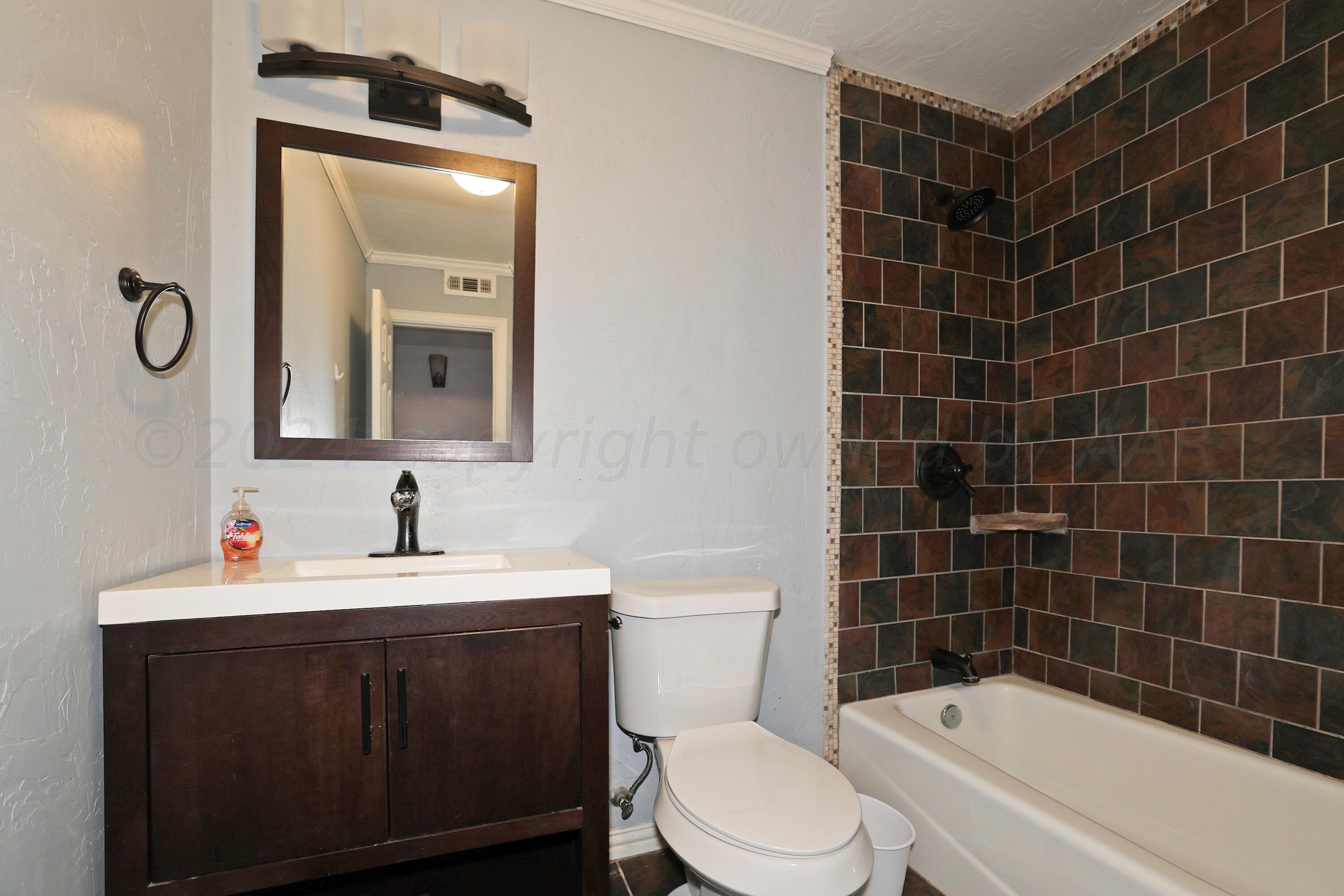 5206 South Travis Street Amarillo, TX 79110 - Photo 18 of 21 a bathroom with a sink a toilet and mirror