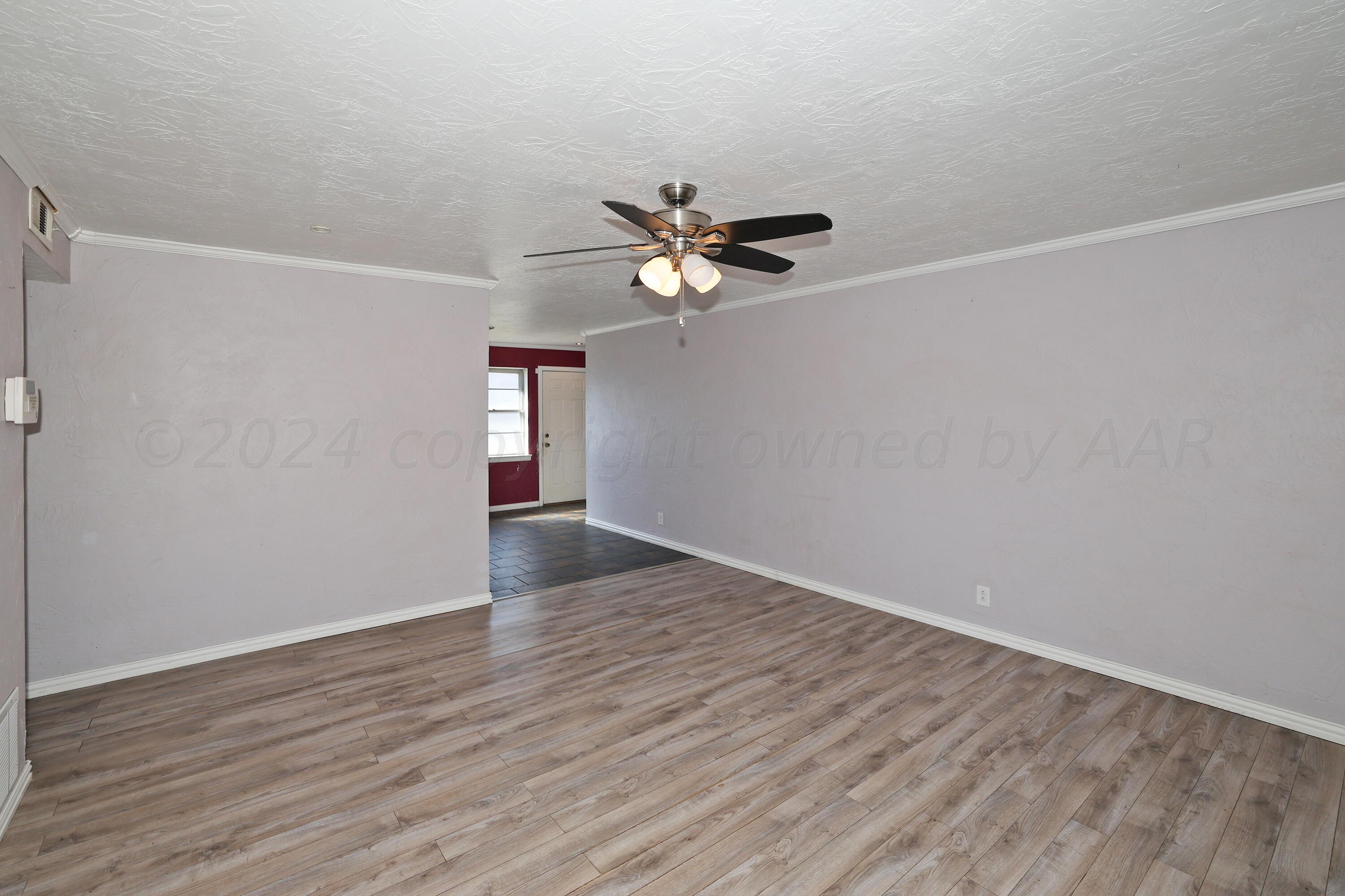 5206 South Travis Street Amarillo, TX 79110 - Photo 4 of 21 a view of an empty room with wooden floor and a ceiling fan