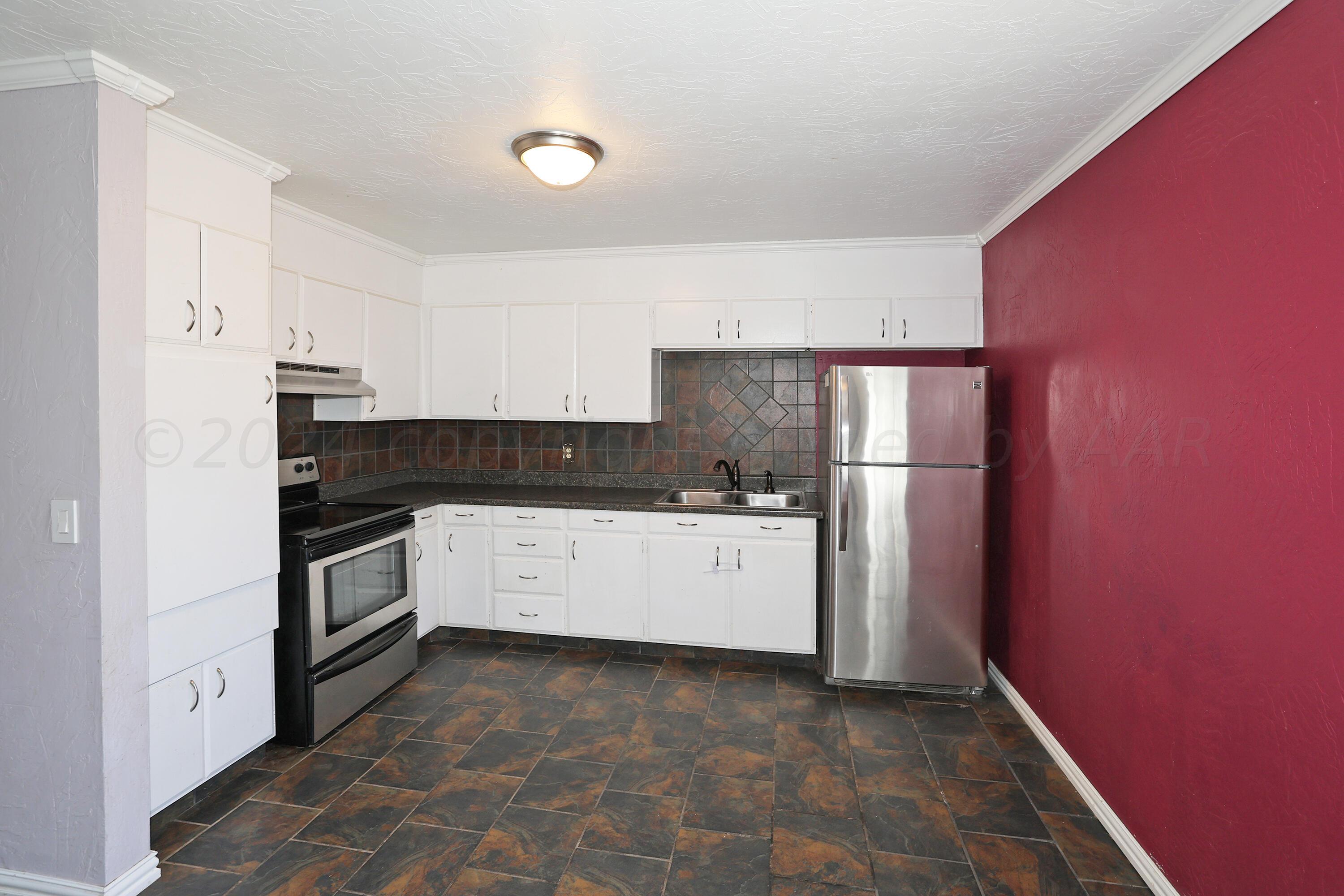 5206 South Travis Street Amarillo, TX 79110 - Photo 9 of 21 a kitchen with a refrigerator stove and white cabinets