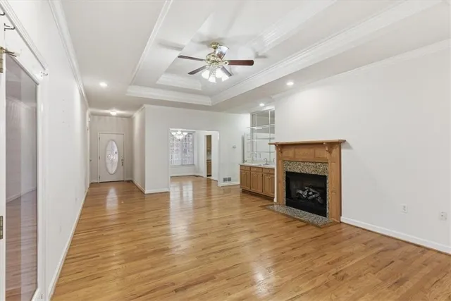 a view of an empty room with wooden floor fireplace and a window