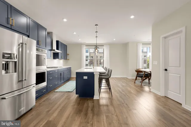 a kitchen with stainless steel appliances granite countertop a refrigerator a stove top oven a sink dishwasher and white cabinets with wooden floor