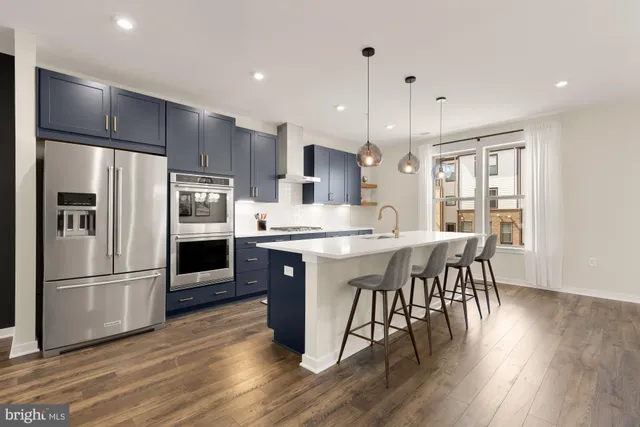a large kitchen with a center island wooden floor stainless steel appliances and windows