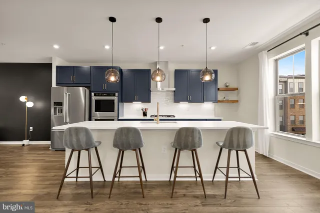 a kitchen with stainless steel appliances granite countertop a table chairs sink and wooden floor